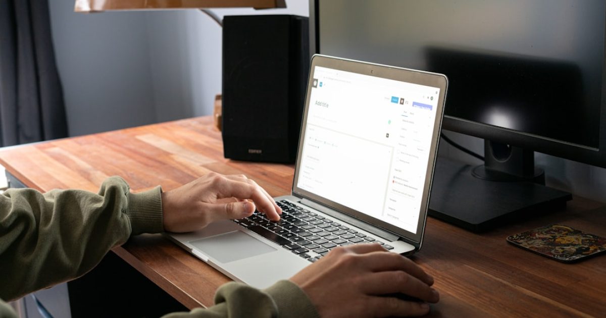 Mãos a trabalhar num portátil com o logótipo do WordPress no ecrã, simbolizando a gestão de atualizações de um website.