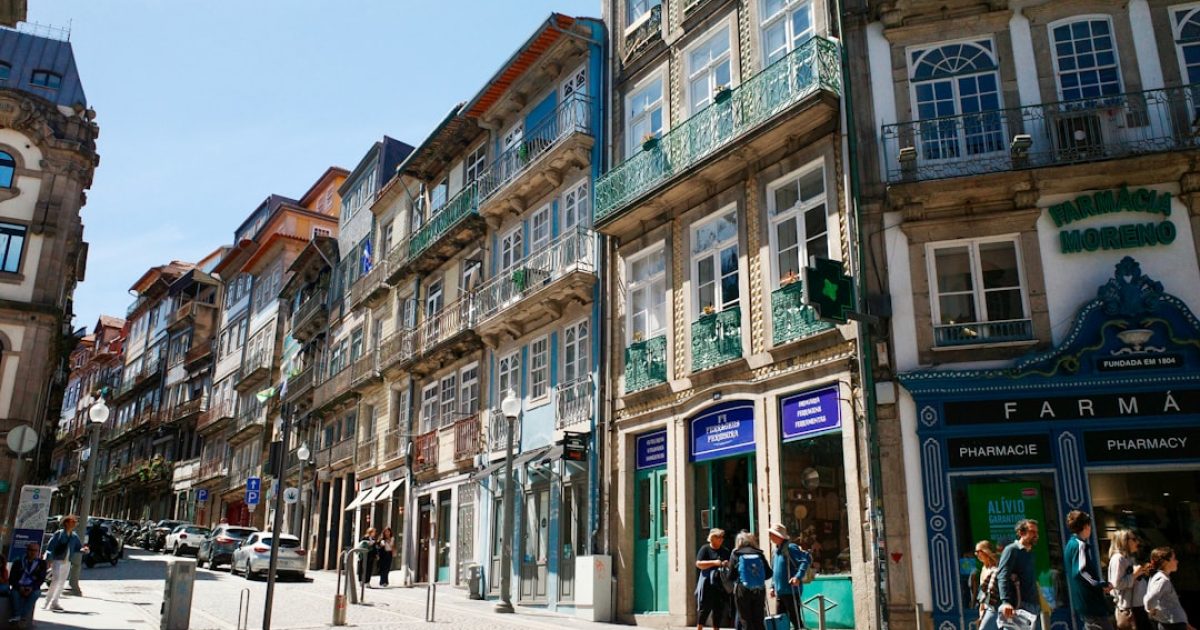 Um empresário português a olhar para dois monitores com os domínios .pt e .com, simbolizando a escolha entre identidade local e alcance global.